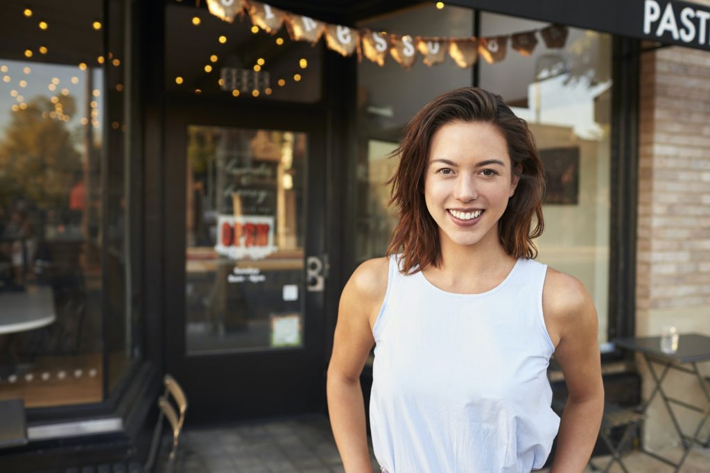 Female business owner standing in the street outside cafe